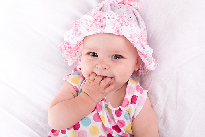 Smiling picture of baby with one hand in mouth