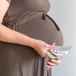 A pregnant lady holds lots of medicine strips