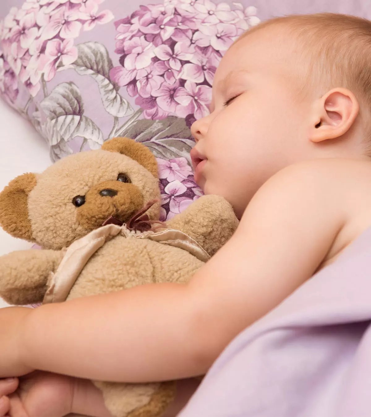 A Baby Holding A Teddy And Sleeping On One Side