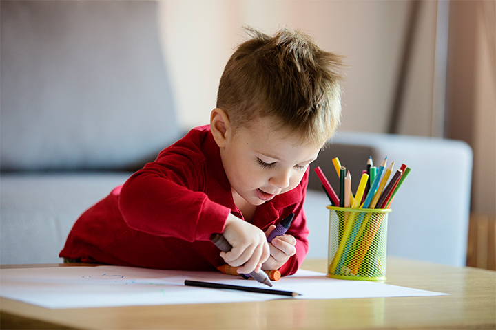 Preschooler drawing on a white paper 