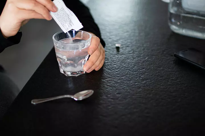 Pour water into a glass and mix ORS for babies