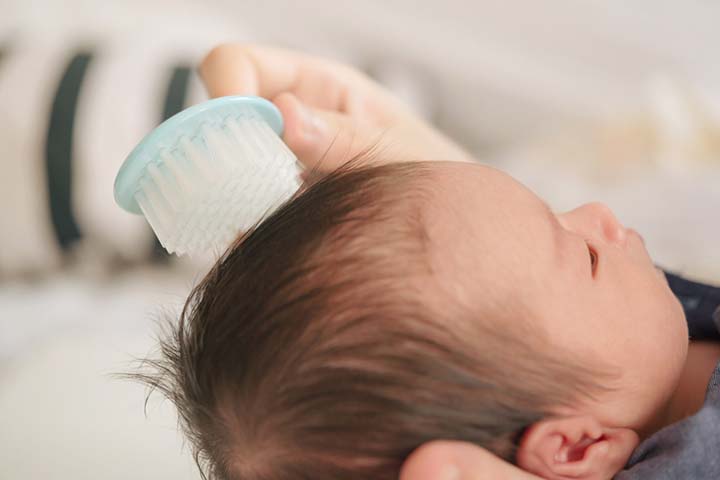 Brush the baby’s dry hair to remove dandruff