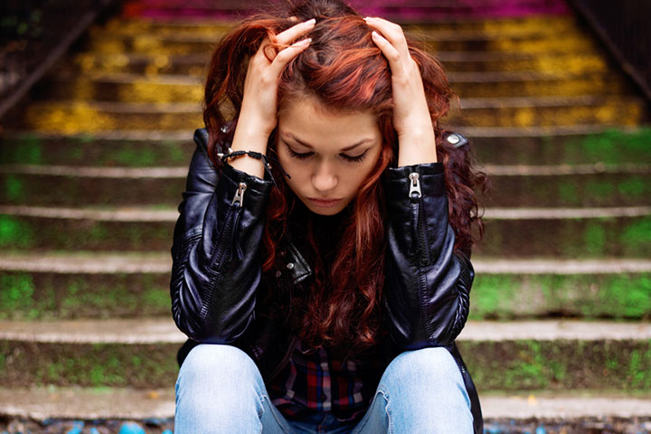 Depressed teenager sitting all alone on colorful stairs. 