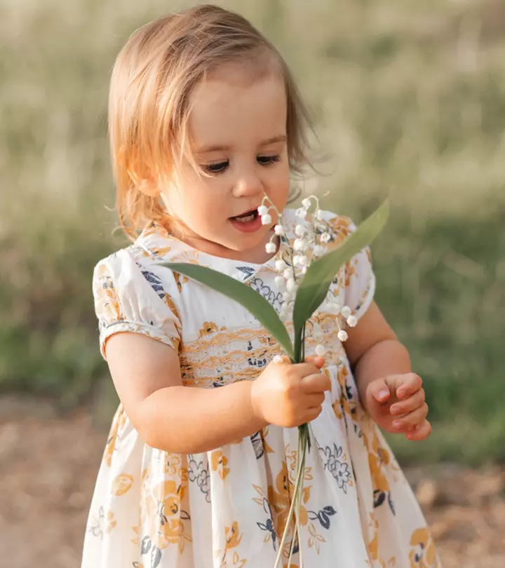 A baby girl holds some grass